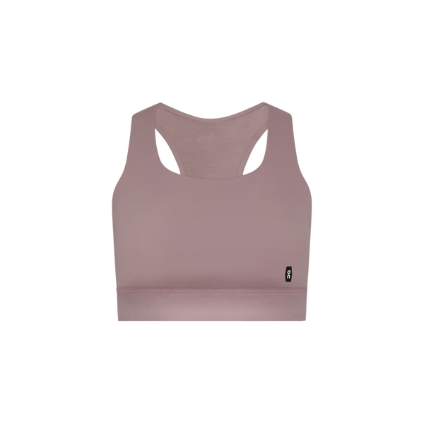 Core Bra, Dame fra On i farven Heron - en komfortabel sports-bh med racerback og lille sort logo-tag på venstre side, perfekt til løb. Præsenteret mod en hvid baggrund.