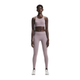 En kvinde kigger fremad i On's Performance Tights, Dame, Heron, sammen med en sports-bh og hvide sneakers på en almindelig hvid baggrund.