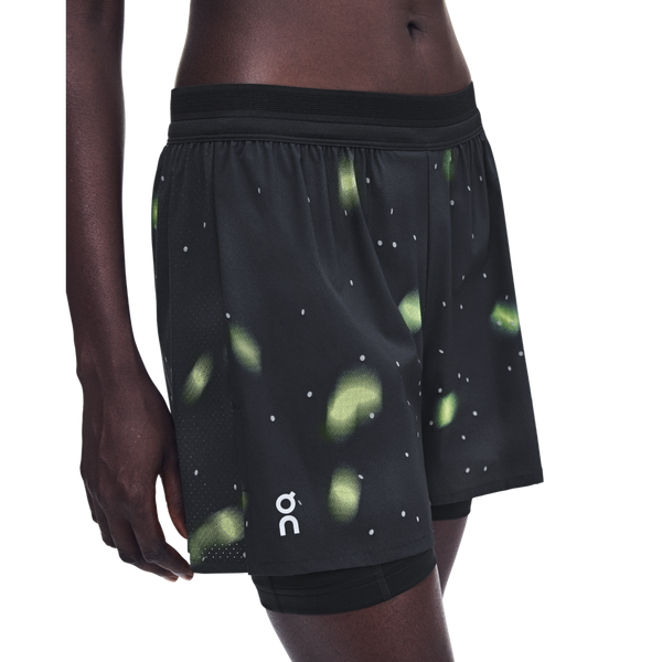 Lumos-træningsshorts til kvinder, sorte med et grønt mønster i bioluminescerende stil og indershorts.