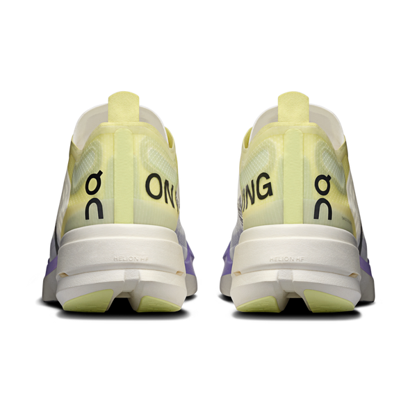 Et par On Cloudboom Strike-sko til mænd i Juniper/Limelight set bagfra, der viser et gult og hvidt design med sort "ON"-branding og tykke hvide såler mærket "HELION HF".