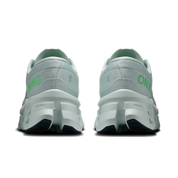 Et par ON Cloudmonster 3 herreløbesko i farven Brook/Flurry, set bagfra med teksten »ON RUNNING« i grønt på hælene og en tyk hvid CloudTec-sål med sort mønster nedenunder.
