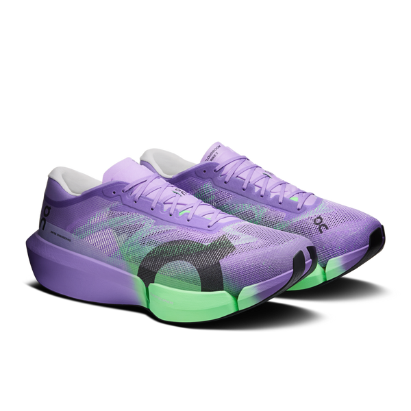 Et par ON Cloudboom Strike 2 unisex-løbesko i farvekombinationen Aconite/Verdite, der fremviser en livlig lilla overdel med dynamiske grønne og sorte detaljer langs siderne og sålen, suppleret af et friskt hvidt inderfor, præsenteret på en ensfarvet hvid baggrund.