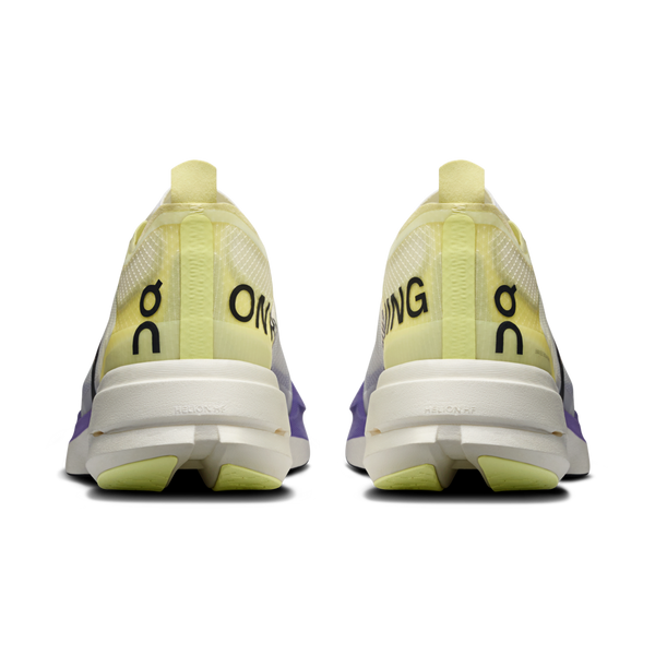 Et par On Cloudboom Strike Dame-sko i Juniper/Limelight ses bagfra og har et gult og lilla gradientdesign med "ON" trykt lodret og et lille logo over det på hver hæl - ideelt som konkurrencesko.