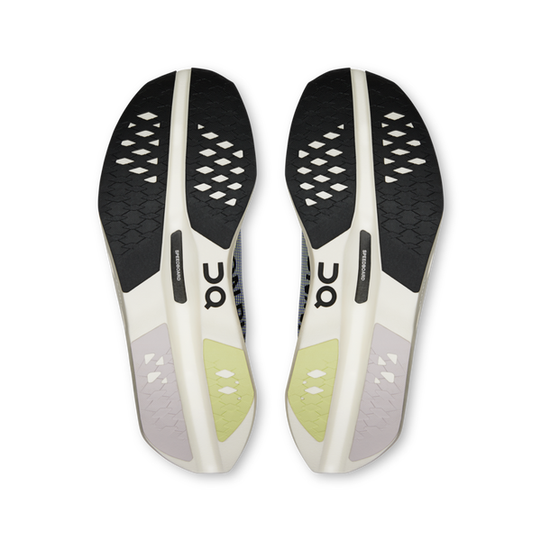 Sålerne på On Cloudboom Volt Dame i Juniper/Limelight er vist med forsiden opad, med sorte, beige og lysegrønne ydersåler med diamantformede slidbaner og ON-logoet nær midten.