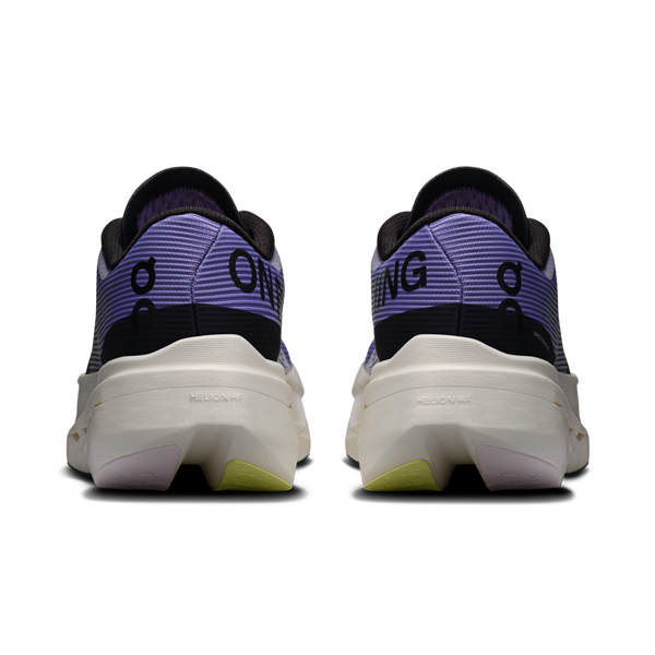 Et kig bagud på On Cloudboom Volt løbesko dame i Juniper/Limelight med lilla overdel, sorte detaljer og hvide chunky såler. "ON" står på venstre hæl og "ING" på højre - ideelt for fans af tempotræning eller Cloudboom Volt.