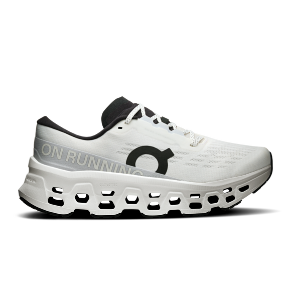 On Cloudmonster 3 Dame i hvid/hvid er en sportssko med en tyk, ventileret CloudTec-sål, sort logo og pløs, sort inderfor, hvide snørebånd og ON RUNNING-tekst på siden.