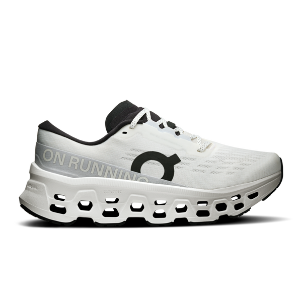 On Cloudmonster 3 Dame i hvid/hvid er en sportssko med en tyk, ventileret CloudTec-sål, sort logo og pløs, sort inderfor, hvide snørebånd og ON RUNNING-tekst på siden.