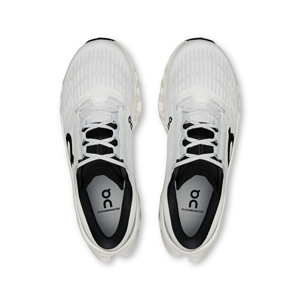 Ovenfor ses et par On Cloudmonster 3 Dame-sneakers i hvid/hvid med sorte detaljer. På indersålerne står der "CLOUDSWIFTER" og et On-logo. Skoene har CloudTec-støddæmpning og hviler side om side på en hvid baggrund.