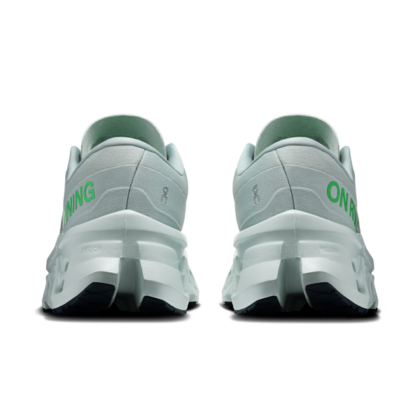 Et par ON Cloudmonster 3 Dame-løbesko i farven Ivory/Topaz, set bagfra med tykke hvide CloudTec-såler og teksten »ON RUNNING« i grønt på hælen, mod en ensfarvet hvid baggrund.