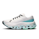 ON Cloudmonster 3 Hyper, Dame i farvekombinationen Ivory/Flurry, er en hvid sportssko med sorte snørebånd, en mellemsål i blå farveovergang og grønne detaljer på ydersålen. Den byder på maksimal dæmpning og karakteristiske udskæringer og vises her i profil mod en ensfarvet baggrund.