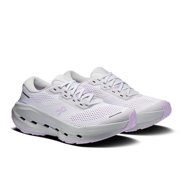 Vi præsenterer On Cloudrunner 3 Max-løbeskoene til kvinder i farven Frost/Verbana: Et par hvide, sporty løbesko designet til maksimal komfort, med lette lilla detaljer, åndbare mesh-overdele og tykke, stødabsorberende såler inspireret af Cloudrunner 3 Max. Skoene har snørebånd og vises på en hvid baggrund.