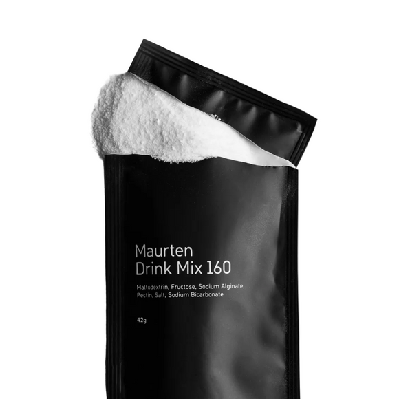 En sort Maurten Drink Mix 160-pakke med hvidt pulver, der løber ud af den åbne top; forsiden viser ingredienser og produktvægt.