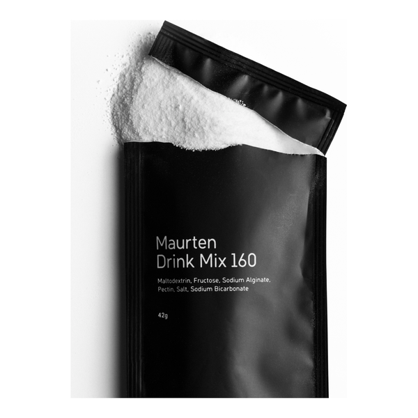 En sort Maurten Drink Mix 160-pakke med hvidt pulver, der løber ud af den åbne top; forsiden viser ingredienser og produktvægt.