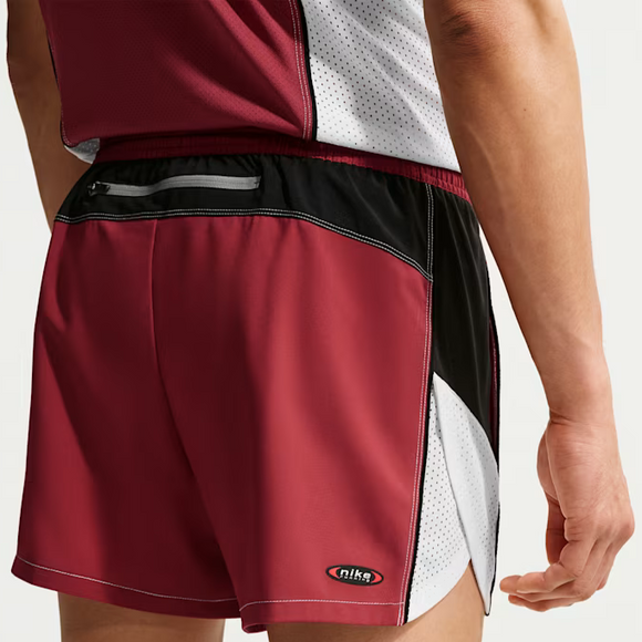 En person er iført Nike Retro 4" kortforede løbeshorts, Herre, i Team Crimson/Black/Reflective Silver med en lille lynlåslomme bagpå og en ærmeløs sportstop. Dri-FIT-teknologi giver komfort, mens shortsens design og logo ses bagfra.