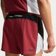 En person er iført Nike Retro 4" kortforede løbeshorts, Herre, i Team Crimson/Black/Reflective Silver med en lille lynlåslomme bagpå og en ærmeløs sportstop. Dri-FIT-teknologi giver komfort, mens shortsens design og logo ses bagfra.