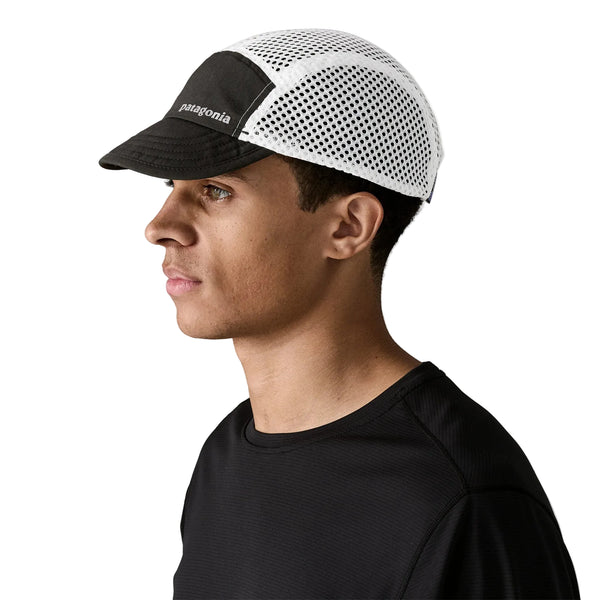 En person i profil mod en hvid baggrund bærer en sort skjorte og en Patagonia Duckbill Cap, Unisex, Black w/Black.