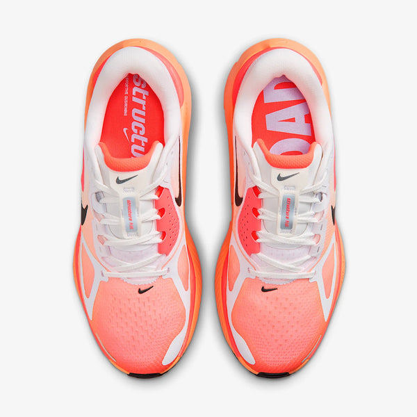 Et par Nike Structure Plus Dame løbesko i farven White/Black-Hot Lava-Orange Pulse set fra oven med sorte swooshes og pink indersåler, hvor venstre siger "Structu" og højre "ROAD". Perfekt til daglig træning.