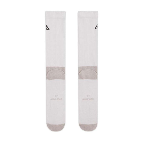 Et par hvide Nike Ed Elvd Crew Socks (unisex) i Photon Dust/College Grey med grå hæl/tå, lille sort trekantlogo øverst og DRI-FIT L G-tekst nederst. Strømperne er lagt fladt ved siden af hinanden.