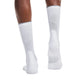 En person står på en hvid overflade iført et par hvide On Elite Run Sock High Hyper-sokker. Billedet, der er taget bagfra, fremhæver bagsiden af personens ben og fødder og viser de ribstrikkede manchetter på disse unisex-sokker til sport.