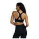 Bagsiden af en kvinde i New Balance træningstøj: Nb Essential Train Bra, Dame, Black, med Y-formet racerback-detalje og matchende sorte leggings.