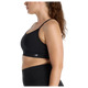 En kvinde med langt brunt hår i hestehale bærer New Balance Essential Yoga Bra, Dame, Black og sorte leggings, vist i profil mod en almindelig hvid baggrund. Bh'en har blødt åndbart materiale og et lille New Balance-logo.