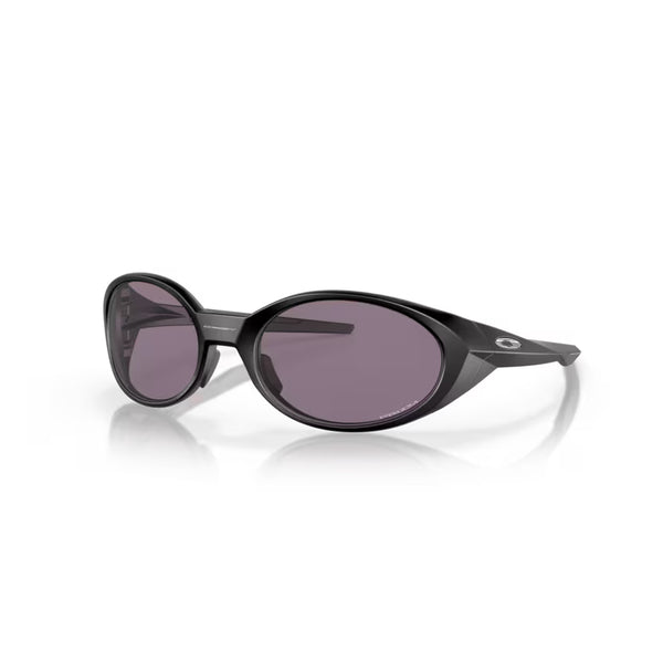 Et par Oakley Eye Jacket Redux solbriller i mat sort, med Prizm Grey linser og glatte ovale stel med en subtil metallisk detalje nær tindingen, vist på en hvid baggrund.