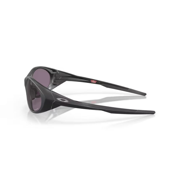 Et par Oakley Eye Jacket Redux-solbriller i Matte Black/Prizm Grey, vist fra en bagsidevinkel på hvid. Med kantede stænger, et lille metallogo og Prizm Grey-glas kombinerer disse solbriller stil og performance.