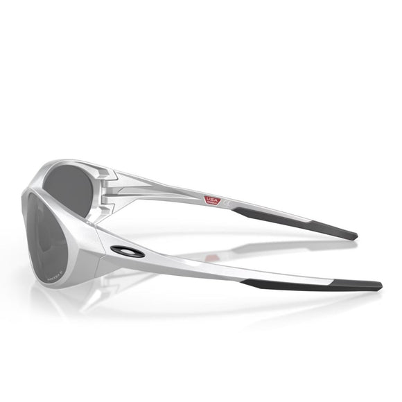 Sølvfarvede Oakley Eye Jacket Redux-solbriller med Prizm Black Polarized-linser vises på en hvid baggrund. Stellet har et kantet design, og Oakley-logoet er placeret på venstre stænger.