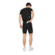 En mand set bagfra, iført en sort T-shirt og et par Flow+ Race Short Tights 7″, Herre, Sort med en baglomme, der er åben, hvide sokker og hvide sneakers.