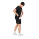 En mand iført sorte Saysky Flow+ Race Short Tights 7″, Herre, Black og en sort T-shirt tager en smartphone frem fra en lomme på siden af sine shorts.