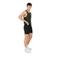 En mand står foran en ensfarvet hvid baggrund iført en mørkegrøn tanktop og Saysky Flow Shorts 5′’, Herre i sort. Han lægger et lille kort eller en genstand i lommen på sine shorts, som han har kombineret med hvide sokker og sportssko for at skabe et elegant, sporty look, der er perfekt til den moderne herre.