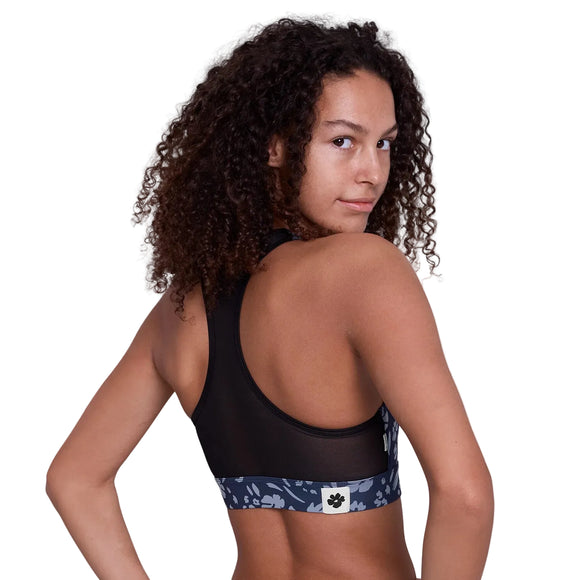 En person med krøllet hår ses bagfra iført Saysky Flower Combat Sports Bra, Dame, Blue Flower - dens åndbare sports-bh-design gør den perfekt til højintensivt løb.