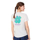 En kvinde med en brun fletning ses bagfra iført en hvid Saysky Flower Combat T-shirt, Dame, med en stor blågrøn og lilla blomstergrafik og "SAYSKY COPENHAGEN" på ryggen. Hun kombinerer den med marineblå shorts.