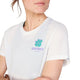 En kvinde bærer Saysky Flower Combat T-shirt i hvid med en grøn kløver og "SAYSKY COPENHAGEN" på brystet; kun hendes underansigt og overkrop er synlige.