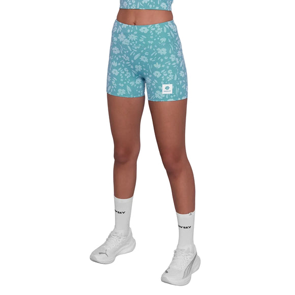 En person er iført en matchende lyseblå crop top og Saysky Flower Combat+ Short Tights 4" (Dame, Light Blue Flower) med et hvidt blomsterdesign, sammen med hvide sportssokker og sneakers. Personens hoved er ikke synligt på billedet.