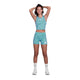 En person står med hænderne bag hovedet iført Saysky Flower Combat Crop Top, Dame, Light Blue Flower - perfekt til løbere - sammen med matchende shorts, hvide sokker og sneakers på en almindelig hvid baggrund.