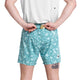 En person står med ryggen til, iført hvid skjorte og Saysky Flower Pace Shorts 5" Herre in Light Blue Flower, og holder et stykke sæbe bag ryggen med begge hænder. En lille tatovering er synlig på bagsiden af det venstre ben.