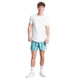 En person står med ansigtet fremad iført en almindelig hvid t-shirt, Saysky Flower Pace Shorts 5" Herre in Light Blue Flower, hvide strømper og hvide sneakers på en hvid baggrund. De lette shorts har et diskret blåt blomstermønster.