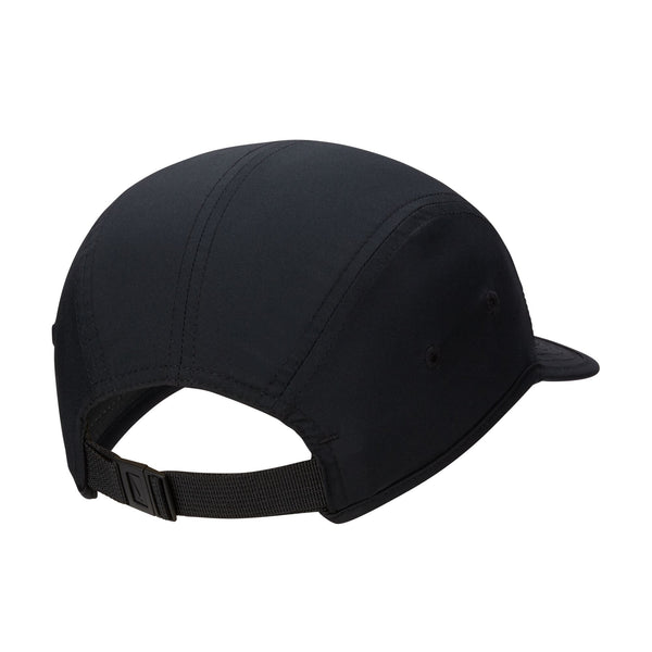 En sort unisex Fly Dri-Fit Unstructured Swoosh-kasket fra Nike ses set bagfra, hvor de synlige sømme, de to øjer i siderne og en justerbar rem med en plastikspænde fremhæves. Kasketten minder om klassiske løbekasket-modeller som Nike Dri-FIT Swoosh-kasketten, og skyggen er delvist synlig i forgrunden til højre.