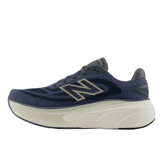 New Balance FreshFoam More v6 løbesko herre i Graphite/Vintage Indigo/Shipyard har en tyk hvid sål, grå og blå detaljer og et stort N-logo, der er designet til maksimal komfort, vist i sideprofil mod hvid baggrund.