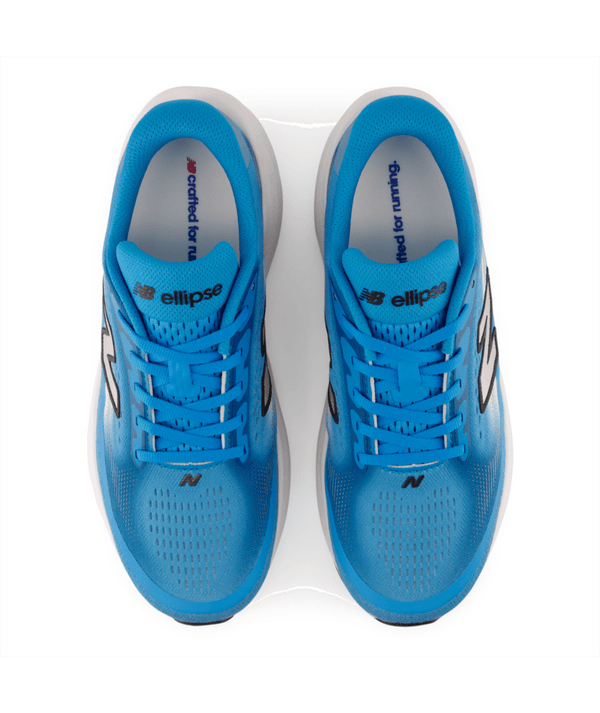 Et par løbesko i levende blå farve fra serien New Balance Freshfoam Ellipse Dame Altitude x NYC Marathon ses set ovenfra, med det ikoniske New Balance-logo på siderne og Ellipse-logoet på tungen. Disse dame-løbesko er udviklet med henblik på maksimal komfort og byder på både ydeevne og stil. Indlægssålerne er trykt med teksten »crafted for running«, der hylder ånden i New Balance NYC Marathon.
