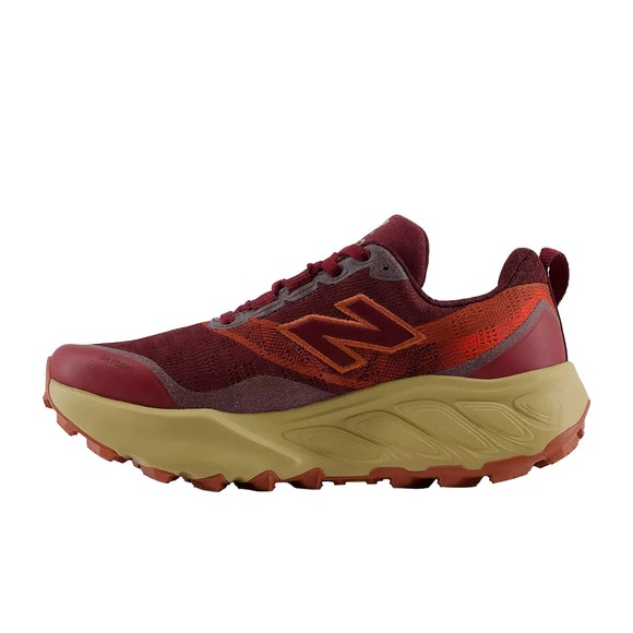 En New Balance Freshfoam Hierro V9 Dame trailsko i farven »Mulled Wine« med maroon- og orange detaljer, en tyk beige sål og et robust mønster – her vist i profil på en ensfarvet hvid baggrund – den perfekte trailsko til kvinder til eventyrlige løbeture eller vandreture.