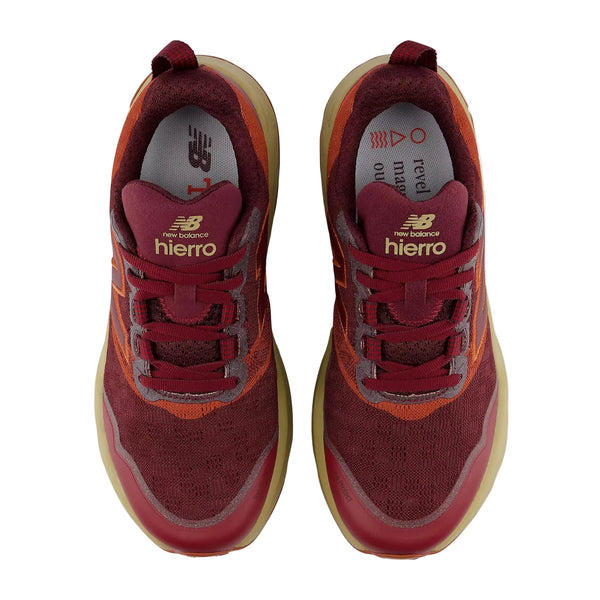 Her ses et par New Balance Freshfoam Hierro V9-sneakers til kvinder i farvekombinationen »Mulled Wine« set ovenfra. De har en overdel i åndbart mesh, guldlogo på tungen og lysebrune ydersåler. Indersålerne er prydet med trykt tekst og grafiske detaljer, hvilket gør disse trailsko til kvinder til en ideel kombination af stil og komfort til ethvert eventyr.