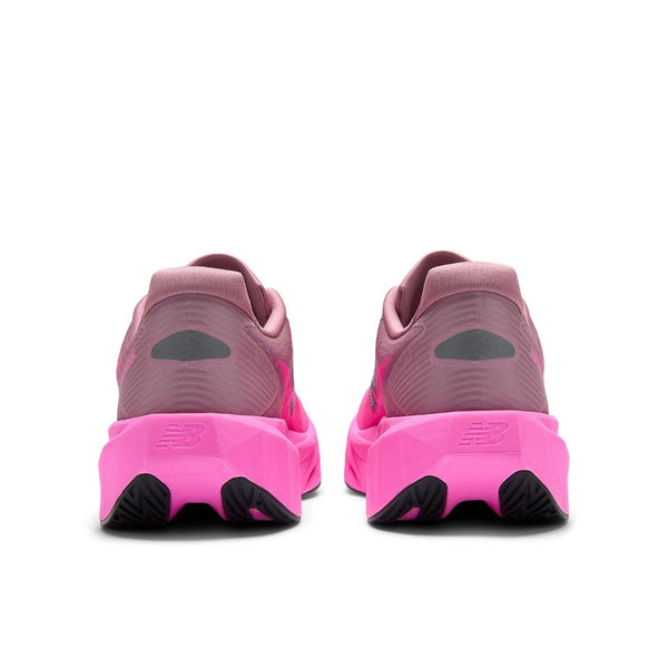 Et par New Balance FuelCell Rebel v5 herre sko i Pink Heat/Rosewood vises bagfra med brandlogo på hælen og sorterer ydersål-perfekte til tempotræning og løb.