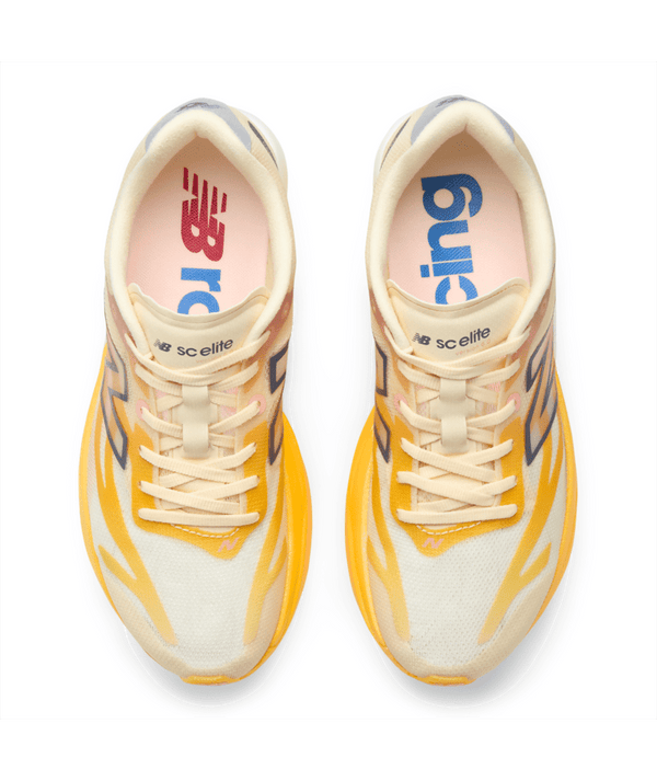 Oversigtsbillede af et par New Balance Fuelcell Supercomp Elite V6 Dame-løbesko i farvekombinationen Satsuma Orange x NYC Marathon, med gule og cremefarvede detaljer, et NB SCE Elite-logo på tungen og New Balance-logoet synligt på de lyserøde indlægssåler. Udstyret med Fuelcell Supercomp Elite-teknologi og en carbonplade for optimal ydeevne.