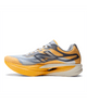 Et billede set fra siden af Fuelcell Supercomp Elite V6 fra New Balance (Herre, Satsuma Orange x NYC Marathon) viser en sportslig løbesko i levende orange og hvid med grå detaljer. Med en overdel i mesh, der sikrer god åndbarhed, en tyk, buet, stødabsorberende sål med carbonplade-teknologi og det ikoniske, stiliserede N-logo på siden er denne konkurrencesko udviklet til løbere, der søger ydeevne i eliteklassen.