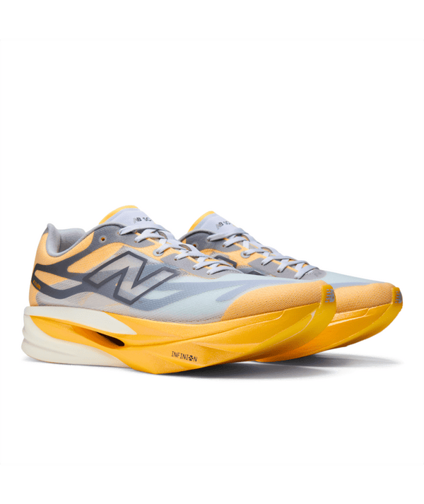 Et par New Balance FuelCell SuperComp Elite V6 konkurrencesko i farven Satsuma Orange, designet til mænd og inspireret af NYC Marathon. Disse løbesko har en tyk, buet sål med et responsivt carbonplade-design og et markant N-logo på siden. Snørebåndene og tungen er hvide.