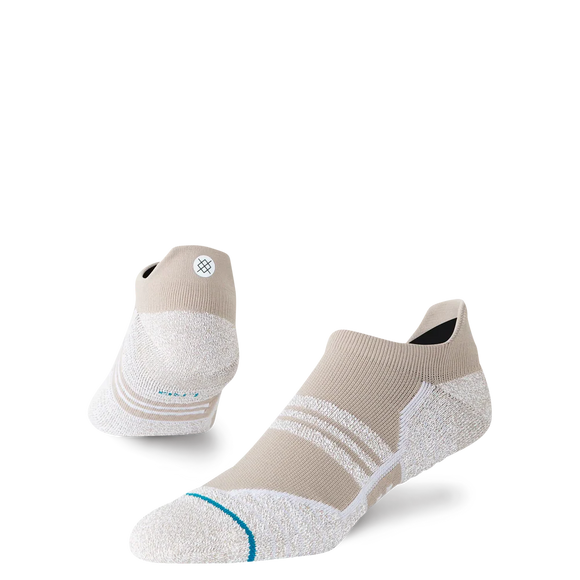 Et par Stance Fusion Grip Tab unisex-sokker i farvevarianten »Croissant«, der har et lavt, sporty design i beige og hvide nuancer, en struktureret sål med Fusion Grip Tab-teknologi, sidestriber, Stance FreshTek-fugtkontrol og et lille cirkulært logo på hælen – vist på en ensfarvet hvid baggrund.