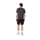 En person vender ansigtet væk fra kameraet i en Liiteguard Ground-Tech T-shirt, Herre, Ebony/Neon Yellow - ideel til løbetræning - med sorte shorts, hvide strømper og sko. Det lugtbekæmpende stof holder dig frisk mod en almindelig hvid baggrund.