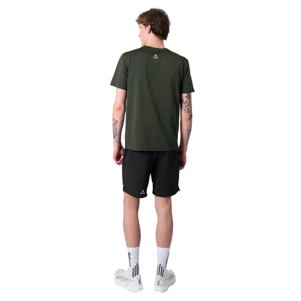 En person står med ryggen til kameraet iført en Liiteguard Ground-Tech T-shirt, Herre, Army Green, sammen med sorte shorts, hvide sokker og hvide sneakers på en almindelig hvid baggrund.